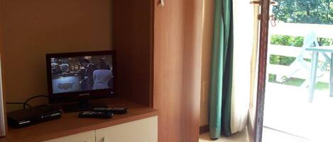 A television on a wooden cabinet, a remote control, and a cable box.