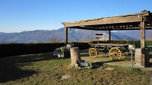 A wooden gazebo with a bench and a cart, set against a backdrop of mountains. - Cottage in Intra With Lake and Mountain Views (Verbania)