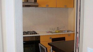 A compact kitchen with a gas stove, oven, and sink. - Cottage in Intra With Lake and Mountain Views (Verbania)