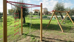A playground with a climbing structure and swings. - Apartment in Monte del Lago Near Lake Trasimeno (Magione)