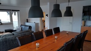 Een moderne eetruimte met een houten tafel, zwarte stoelen en hanglampen.