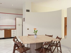 A modern kitchen with white cabinets, a wooden dining table, and chairs. - Belvilla by OYO Vesuvio (Trecase)