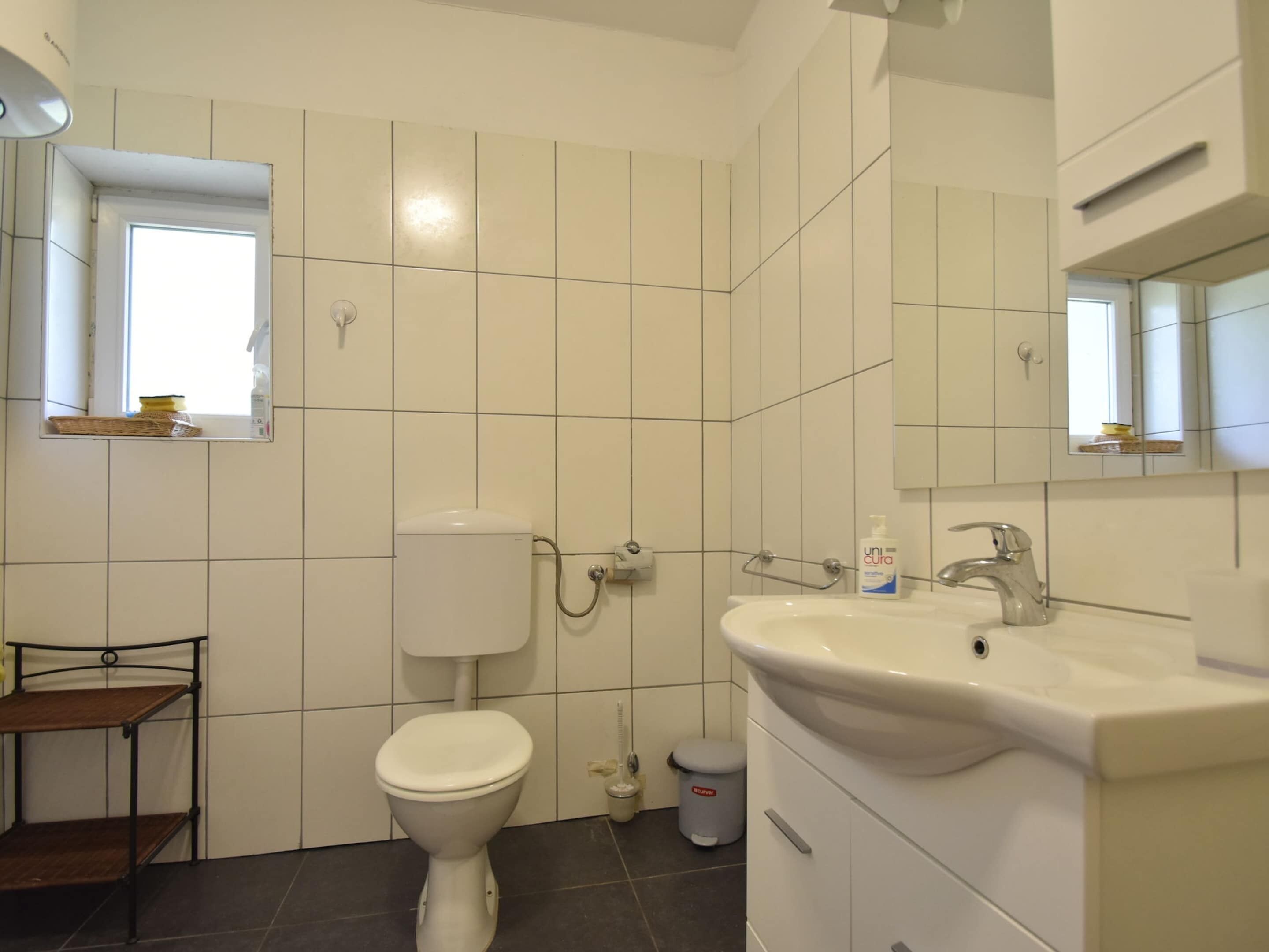 A bathroom with a toilet, sink, and mirror.