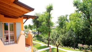 A two-story building with a balcony, a garden with a pathway, and outdoor furniture. - Belvilla by OYO Attractive Residence on Lake Garda (Manerba del Garda)