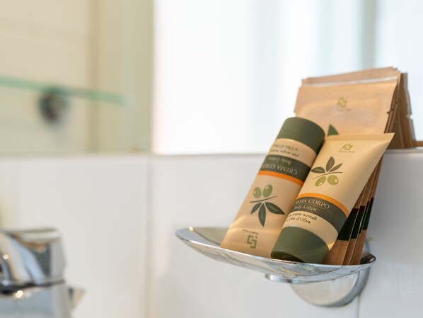 Un baño con un estante que contiene dos botellas de loción corporal y un tubo de crema.