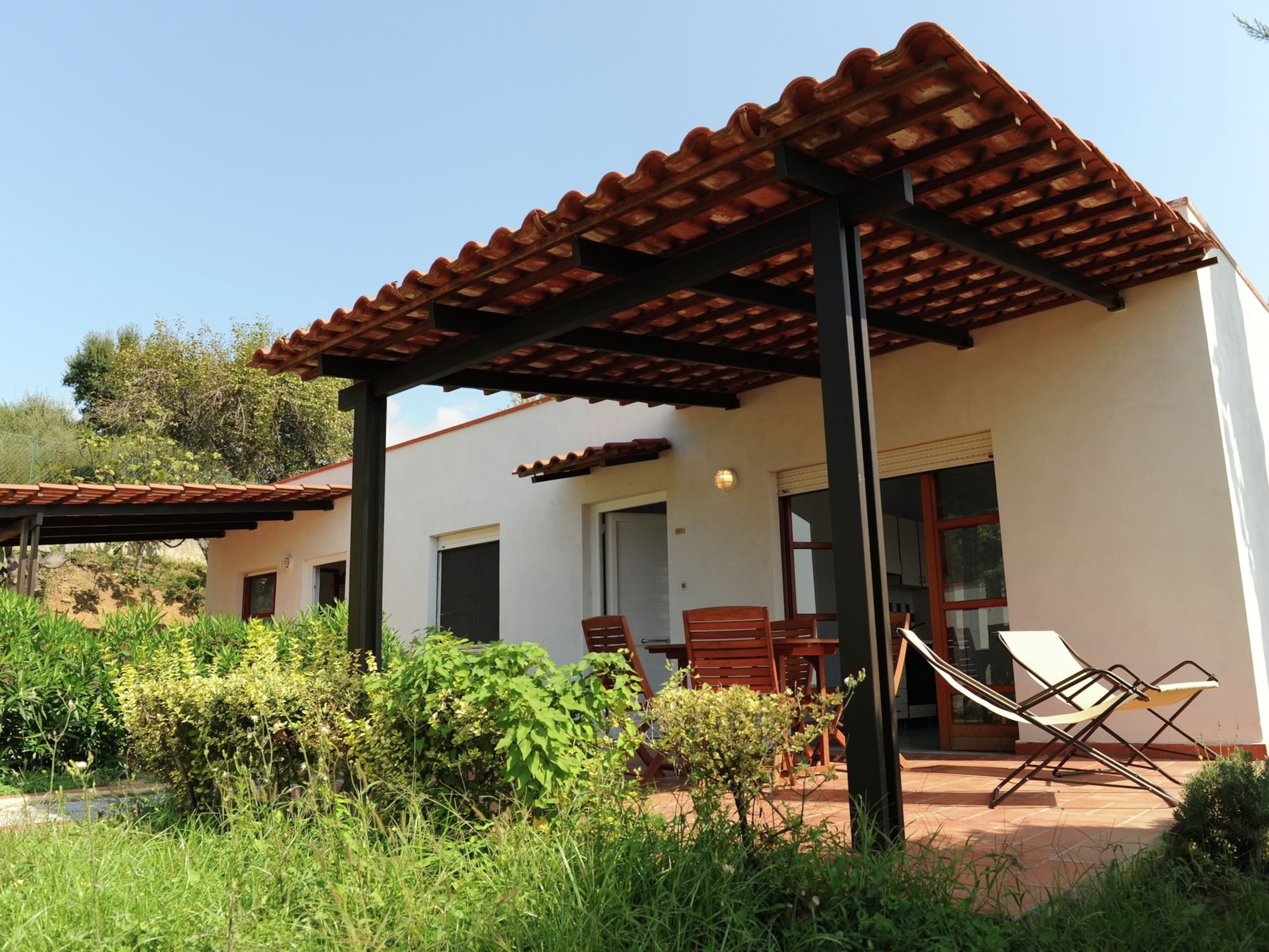 A modern house with a patio area, outdoor seating, and a pergola.