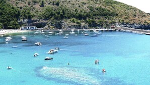 A coastal area with boats on clear blue water, a hilly backdrop, and a building with a white facade. - Romantic Escape w/ Terrace (Centola)