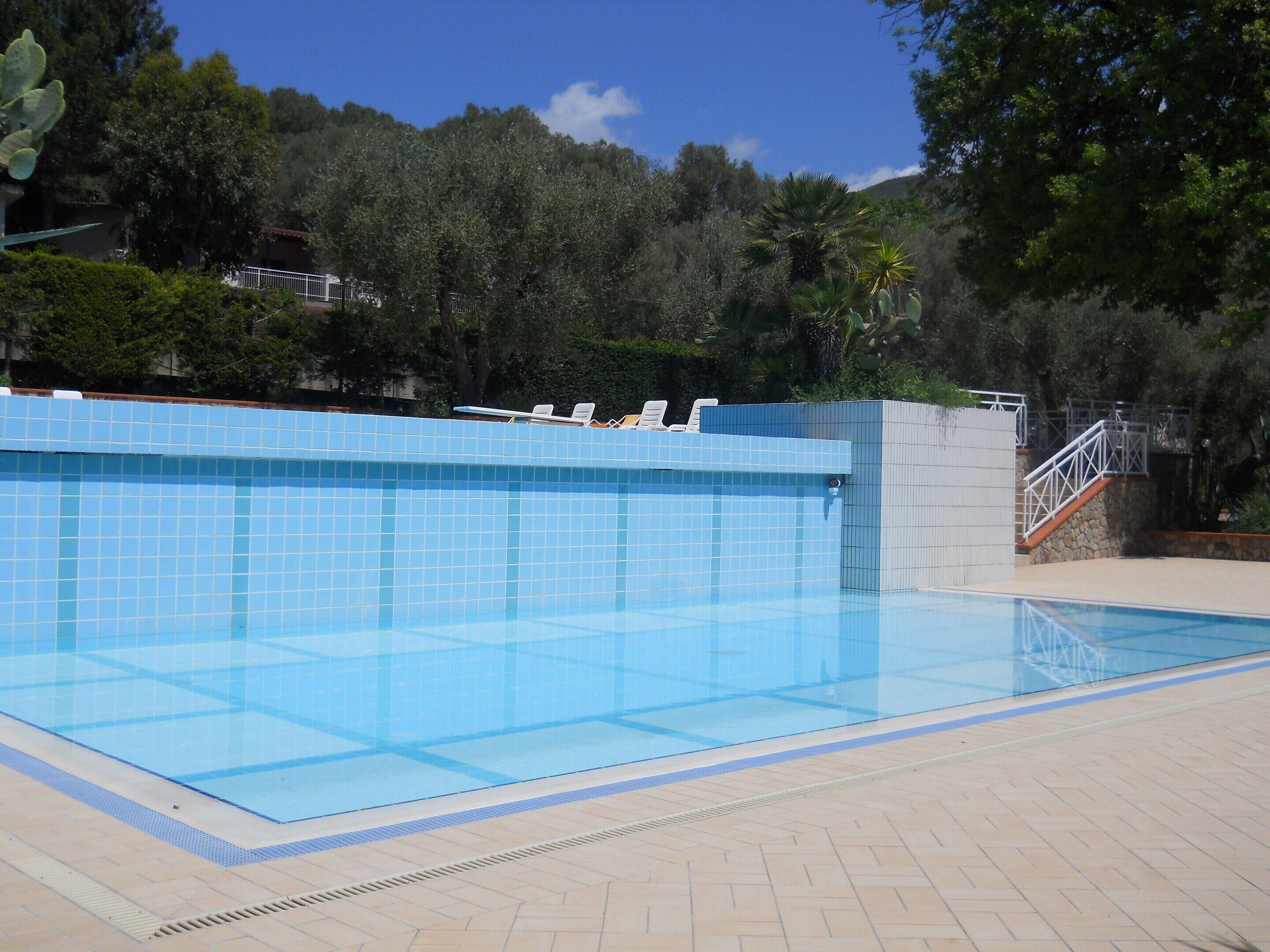 A swimming pool with tiled walls and a tiled deck area.