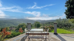 An outdoor patio with a table and chairs, a stone floor, and a view of a mountainous landscape. - Dwelling in Renovated Barn near Birthplace of Michelangelo (Caprese Michelangelo)