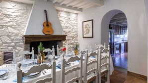 A dining area with a stone wall, a guitar, and a framed artwork.