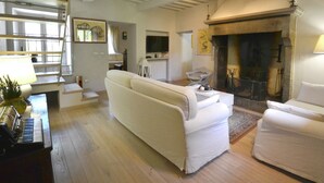 A living room with a fireplace, a sofa, a television, and a piano.