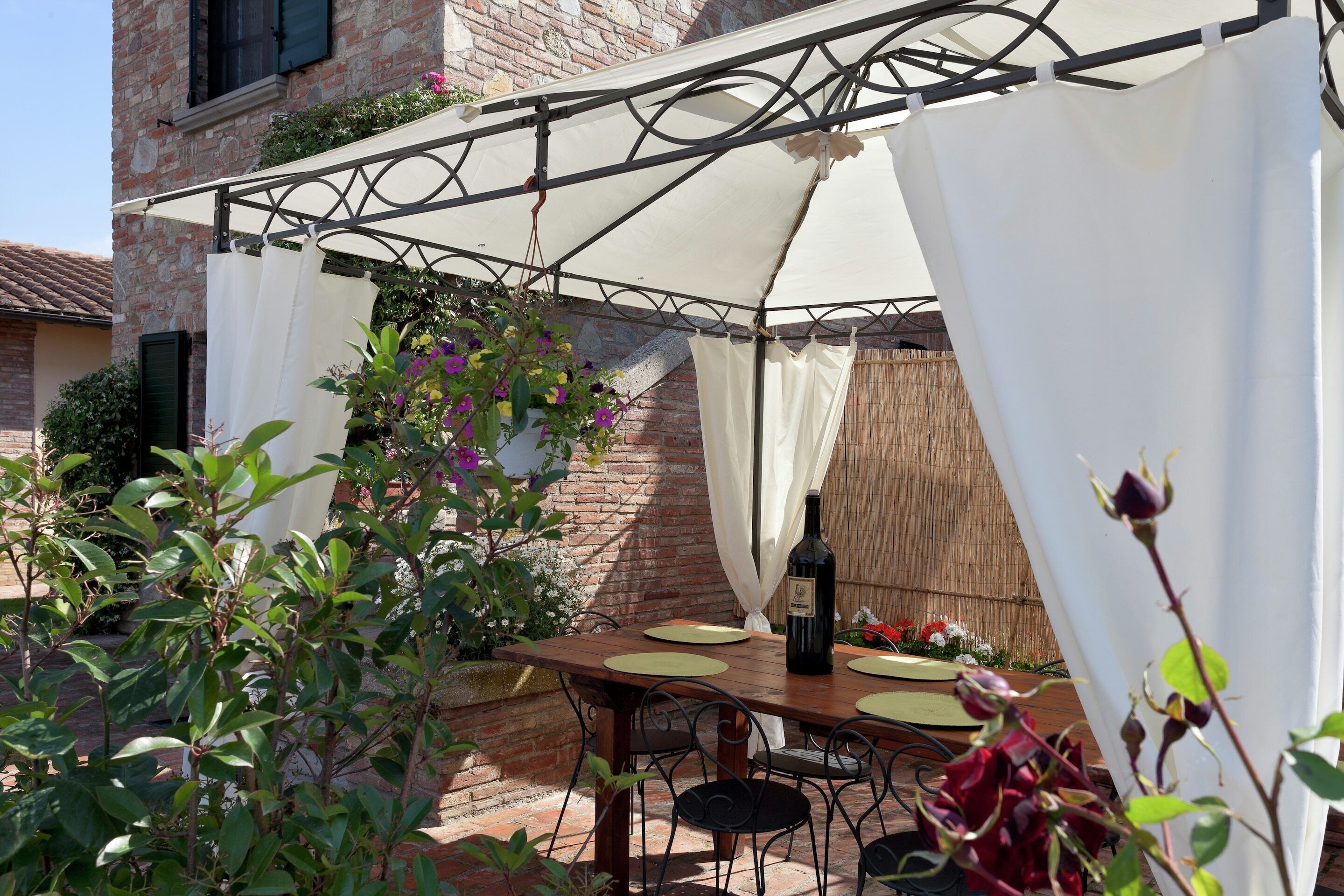Eine Terrasse im Freien mit einem Holztisch, Stühlen und einem weißen Sonnensegel.