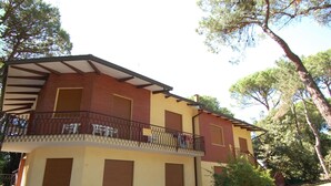 A two-story building with a balcony, a small garden, and a brick facade. - Belvilla by OYO Elios Trilo Due (Rosolina)