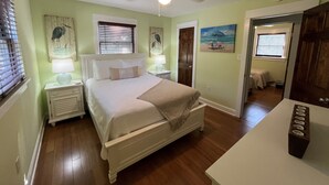 Un dormitorio con una cama, mesitas de noche, ventilador de techo y obras de arte en las paredes.
