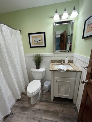 A bathroom with a toilet, sink, and shower curtain. - Swept Away One -Great Family Beach Home (Kill Devil Hills)