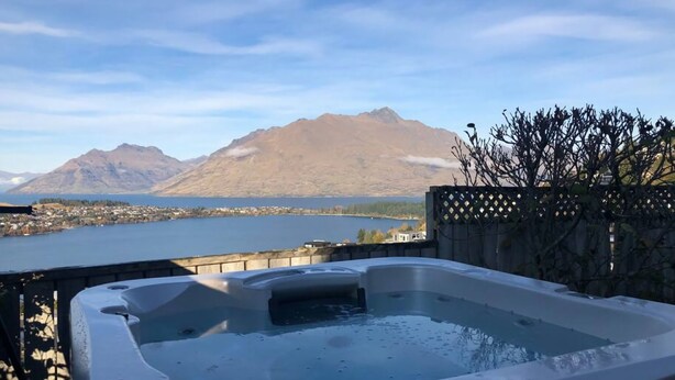 A hot tub with a view of a lake and mountains.