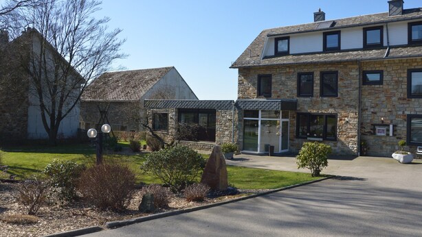 A stone building with a glass entrance, a stone facade, and a well-maintained lawn. - Liege Cottage With Sauna (Waimes)
