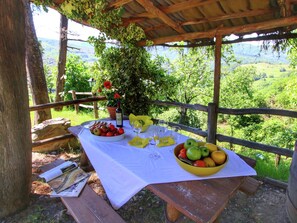 An outdoor picnic setup with a table set for two, surrounded by a wooden fence and lush greenery. - Charming Tuscan Farmhouse (Ortignano Raggiolo)