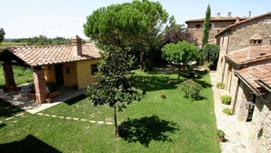 A courtyard with a yellow building, stone walls, and a large tree. - Quiet Farmhouse in Cortona (Cortona)