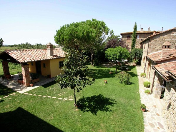 A courtyard with a yellow building, stone walls, and a large tree. - Quiet Farmhouse in Cortona (Cortona)