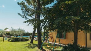 A sunny outdoor area with a swing set, a pool, and a yellow building. - Quiet Farmhouse in Cortona (Cortona)