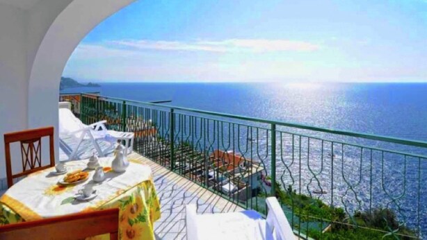 A dining area with a table set for two, overlooking a scenic view of the sea. - Apartment near Praia with Large Terrace & Spectacular Views (Praiano)
