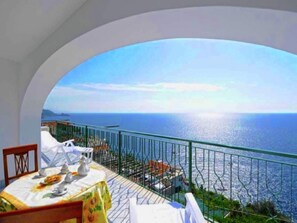 A dining area with a table set for two, overlooking a scenic view of the sea. - Apartment near Praia with Large Terrace & Spectacular Views (Praiano)