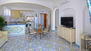 A compact living space with a kitchen, dining area, and a TV. - Apartment near Praia with Large Terrace & Spectacular Views (Praiano)