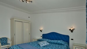 A bedroom with a bed, a wardrobe, a chair, and two bedside tables. - Apartment near Praia with Large Terrace & Spectacular Views (Praiano)