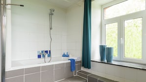 A bathroom with a bathtub, shower, and a window with curtains. - Farm With Lovely Panoramic Views (Trois-Ponts)