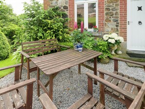 A wooden bench and table set on a gravel surface with a stone building in the background. - Farm With Lovely Panoramic Views (Trois-Ponts)