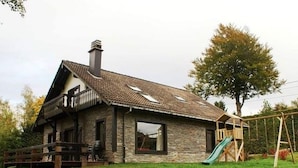 A stone house with a tiled roof, a balcony, and a slide in the yard. - Apartment in Belgium Near Scenic Trails (Malmedy)