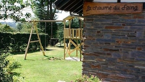 A wooden swing set in a garden with a stone wall and a sign that reads "La chaume du Faing". - Apartment in Belgium Near Scenic Trails (Malmedy)