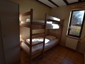 Dormitorio con literas, ventana y radiador.