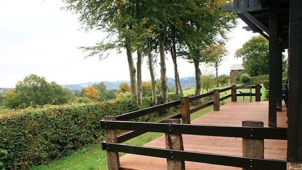 A wooden deck with a railing, surrounded by greenery and trees. - Apartment in Belgium Near Scenic Trails (Malmedy)