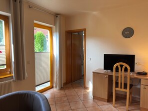 A room with a desk, chair, and a television. There is a window with curtains and a door leading to another room. - Holiday Apartment in the Naturpur Holiday Village (Brakel)