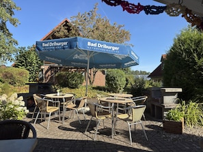 An outdoor seating area with tables and chairs under a blue umbrella with the text 'Bad Driburger.'