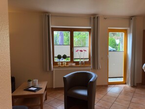 Una habitación con una mesa de comedor, un sofá, una ventana con cortinas y un radiador.