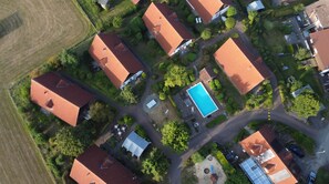 Vista aérea de una zona residencial con varias casas, una piscina y jardines bien cuidados.