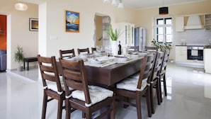A dining area with a long table, wooden chairs, and a painting on the wall. - Attractive Villa With Private Swimming Pool, Beach Volleyball and Fenced Garden (Rasa)