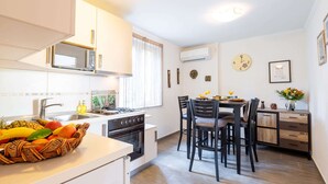 A modern kitchen with white cabinets, a gas stove, and a dining area with four chairs. - Dubrovnik Coastal Gem (Dubrovnik)