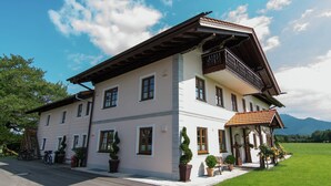 A two-story building with a balcony, potted plants, and a bench outside. - Quaint Holiday Home in Feldwies near Ski Area (Uebersee)