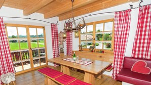 A wooden dining table with benches, a red cushioned bench, and a red sofa with a heart design. - Quaint Holiday Home in Feldwies near Ski Area (Uebersee)
