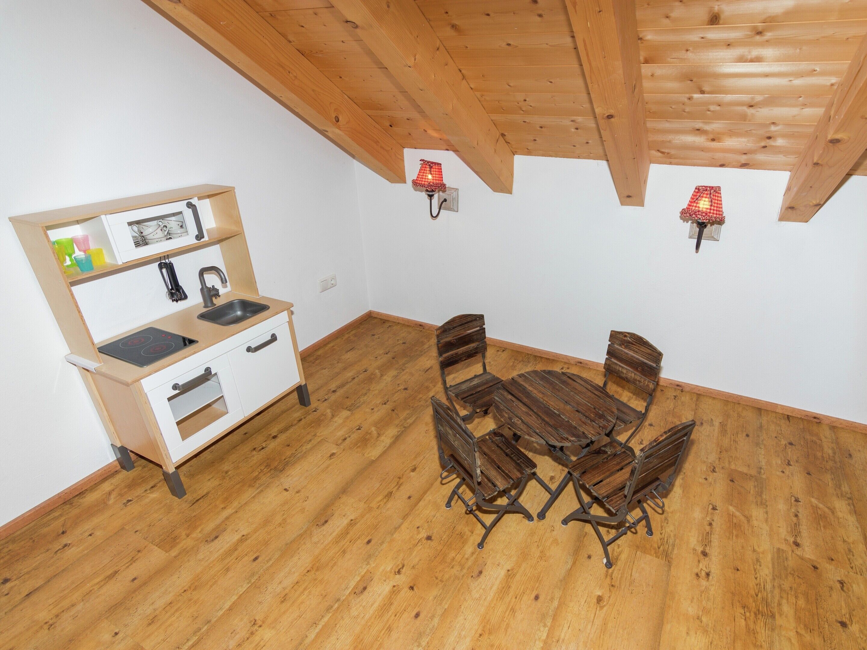 Une cuisine compacte avec une table et des chaises en bois, un four encastré et un évier.