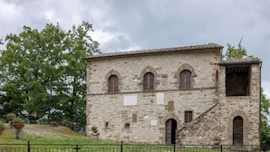 Un bâtiment en pierre doté de fenêtres en arc de cercle et d’un escalier menant à un deuxième étage.
