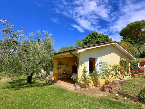 A yellow house with a tiled roof, surrounded by greenery and potted plants. - Belvilla by OYO Casaletto Graffi (Graffignano)