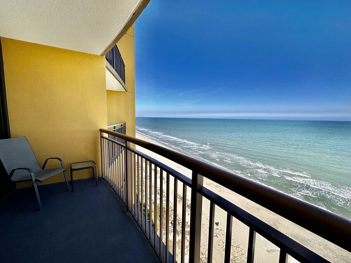 Ein Balkon mit Meerblick, ein Stuhl und ein Geländer.