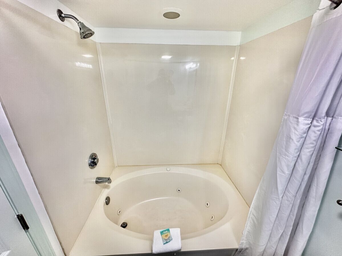 A small, modern bathroom with a bathtub, a showerhead, and a towel rack.