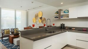 Una cocina moderna con una isla grande, muebles blancos y decoración en la pared.