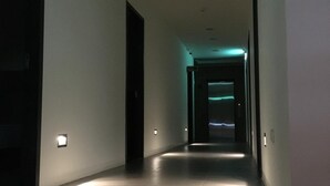 Un pasillo tenuemente iluminado, con un sendero iluminado que conduce a una puerta al final.